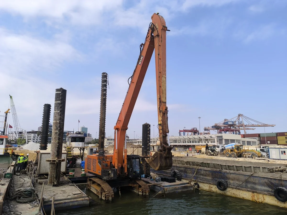 Excavator on a floating platform during harbour dredging