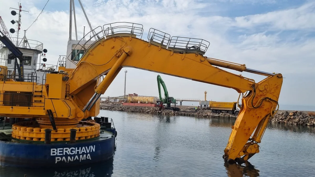 Marine dredger with excavator boom over water